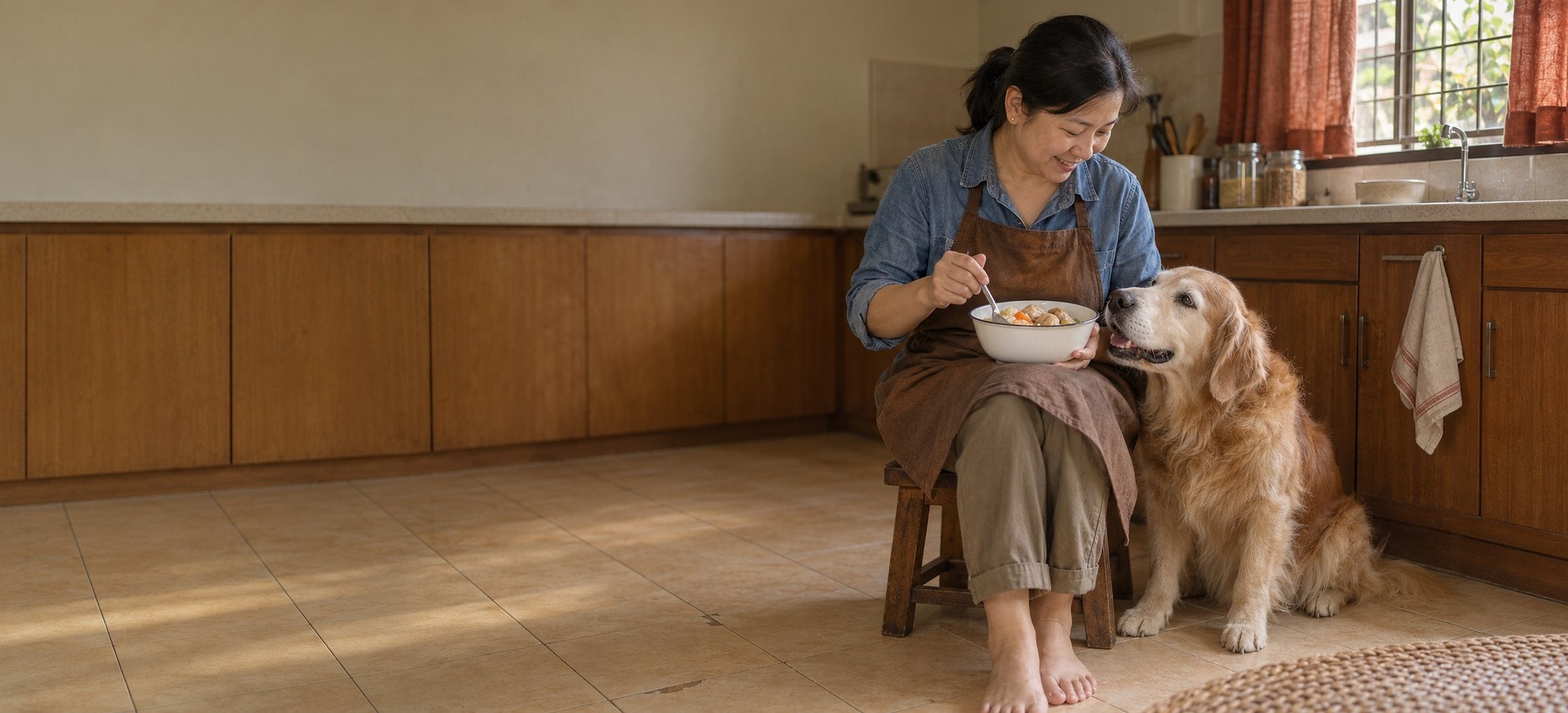 一位女士坐在厨房矮凳上搅拌碗里的食物，她的老金毛紧挨着她坐着，抬头望着她